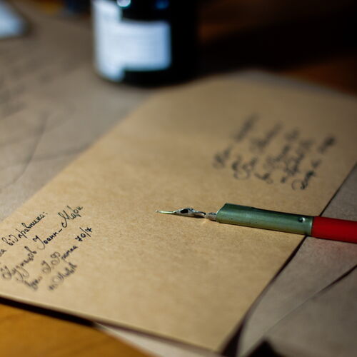 Dekoratives Bild: Tintenflasche, Feder und handgeschriebene Briefe auf Holztisch – keine inhaltlichen Informationen, nur visuelle Gestaltung.